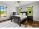 Bedroom with hardwood floors, two windows with green views, and black bedroom furniture at 6700 Folger Dr, Charlotte, NC 28270