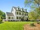 Beautiful two-story white home featuring a manicured lawn, dormer windows, and a charming front balcony at 6700 Folger Dr, Charlotte, NC 28270