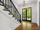 Bright foyer featuring hardwood floors, stairs with a black railing, and a glass-paneled front door at 6700 Folger Dr, Charlotte, NC 28270