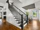Elegant staircase with wood floors and black railing, leading to the dining room with a modern chandelier at 6700 Folger Dr, Charlotte, NC 28270