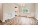 Elegant dining room with wainscoting, a modern chandelier, and wood-look floors next to a large window at 7009 New Town Rd, Waxhaw, NC 28173