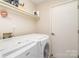 Bright laundry room with a front loading washer and dryer, and overhead shelving at 8224 Park Vista Cir, Charlotte, NC 28226