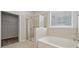 Well-lit bathroom showcasing a glass-enclosed shower, soaking tub, and neutral tile for a clean, modern aesthetic at 896 Exeter Dr, Sherrills Ford, NC 28673
