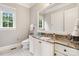 Bright bathroom with vanity featuring marble countertops, white cabinetry, and a large mirror at 9011 Pine Laurel Dr, Weddington, NC 28104
