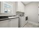 Laundry room with white cabinets, granite countertop and a modern washer and dryer at 125 Trent Pines Dr, Mooresville, NC 28117