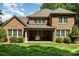 Rear view of the brick home showing covered patio and well-maintained lawn at 13620 Castleford Dr, Mint Hill, NC 28227