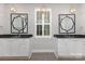 Elegant bathroom featuring double vanities, granite countertops, and decorative mirrors at 13620 Castleford Dr, Mint Hill, NC 28227