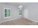Bright bedroom featuring neutral walls, carpet, and a chandelier, illuminated by natural light through shuttered windows at 13620 Castleford Dr, Mint Hill, NC 28227