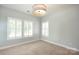 Neutral bedroom featuring large windows with white shutters, a modern light fixture, and ample light at 13620 Castleford Dr, Mint Hill, NC 28227