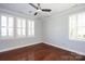 Empty bedroom with ceiling fan, hardwood floors, crown molding, and bright shuttered windows at 13620 Castleford Dr, Mint Hill, NC 28227