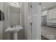 View of half bathroom with pedestal sink, modern mirror, and a view of the open door to the kitchen at 1617 Cannon View Ln, Charlotte, NC 28208