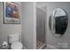 Cozy bathroom featuring a glass-enclosed shower, decorative mirror, and a toilet beneath a colorful art poster at 210 N Church St # 1307, Charlotte, NC 28202