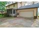 Rear view of a house with a spacious garage, screened porch, and a private gravel driveway at 2131 Wildlife Rd, Charlotte, NC 28214