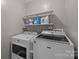 Functional laundry room with modern washer and dryer units and storage shelves at 2439 Heathershire Ln, Matthews, NC 28105