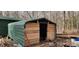 Green metal barn with wood trim, showing a large open door, and grazing goats at 368 Northwood Dr, Troy, NC 27371