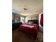 Bedroom features a red comforter, dark furniture, soft carpet, and natural lighting at 368 Northwood Dr, Troy, NC 27371