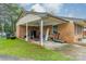 Attached brick carport featuring covered area, brick and white pillar supports, and cluttered storage space at 417 Donna Ave, Gastonia, NC 28052