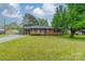 Charming brick ranch with mature tree in front yard, featuring a covered carport, shutters and manicured lawn at 417 Donna Ave, Gastonia, NC 28052