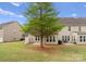 A spacious backyard with green lawn, a large shade tree, and a patio with furniture at 6619 Portland Rose Ln, Charlotte, NC 28210