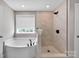 Bathroom featuring bathtub, modern shower with rainfall shower head, and updated tile at 704 Fresia Dr, Tega Cay, SC 29708