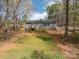 Rear exterior view featuring the home's gray siding, small deck, and partially wooded backyard at 7790 Caswell Rd, Stanley, NC 28164