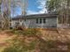 Back exterior showcasing gray vinyl siding, complemented by a small deck and well-manicured yard at 7790 Caswell Rd, Stanley, NC 28164
