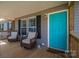 Inviting front porch with wicker chairs, a vibrant teal door, and charming decorative details at 7790 Caswell Rd, Stanley, NC 28164