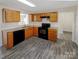 Functional kitchen with oak cabinetry, granite countertops, black appliances, and wood flooring at 808 Raindrops Rd, Gastonia, NC 28054