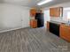 Kitchen featuring wood-look tile flooring, wood cabinets, granite countertops, and black appliances at 808 Raindrops Rd, Gastonia, NC 28054