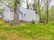 View of the backyard showing the home's exterior, grassy lawn and surrounding trees at 809 N Ransom St, Gastonia, NC 28052