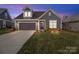 Charming single-Gathering home featuring a manicured lawn, gray siding, and a two-car garage at dusk at 9087 Treetop Nw Way, Concord, NC 28027