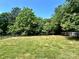 Backyard featuring a sturdy black fence, lush lawn, and mature trees at 9419 Seamill Rd, Charlotte, NC 28278