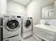 Efficient laundry room featuring front loading washer and dryer and utility sink for added convenience at 9677 Garamont Nw Pkwy, Concord, NC 28027
