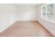 Sunlit bedroom with wood-look flooring, white walls, and a window with bright natural light at 9907 Hagers Rd, Huntersville, NC 28078