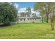 View of the rear exterior with a large grassy yard and charming painted brick at 9907 Hagers Rd, Huntersville, NC 28078