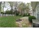 Lush backyard featuring a well-kept lawn, a stone fire pit, white picket fence, and mature trees, perfect for relaxation at 108 Kinderston Dr, Davidson, NC 28036