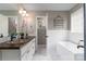 Bathroom with marble floors, a soaking tub, double sink vanity with bronze faucets and wooden countertop at 108 Kinderston Dr, Davidson, NC 28036