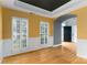 Dining room with hardwood floors, white shutters, yellow walls, tray ceiling, and arched doorway at 108 Kinderston Dr, Davidson, NC 28036