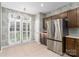 Sunlit kitchen with stainless steel fridge, wood cabinets and large glass doors with white shutters at 108 Kinderston Dr, Davidson, NC 28036