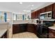 Traditional kitchen features dark wood cabinets, black appliances, and tile flooring at 10920 Walking Path Ln, Charlotte, NC 28213