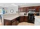 Well-lit kitchen featuring dark wood cabinets, stainless steel appliances, and tiled flooring at 10920 Walking Path Ln, Charlotte, NC 28213