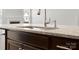 Close up view of kitchen island with stone countertop, stainless steel sink, and dark cabinets at 110 Lantern Acres Dr, Mooresville, NC 28115