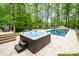 Relaxing backyard with a hot tub, pool, travertine patio, and lush landscaping for serene outdoor enjoyment at 112 Spring Branch Rd, Fort Mill, SC 29715