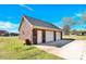 A brick garage with two garage doors and an entry door is set into a green lawn against a blue sky at 115 Green Sw St, Concord, NC 28027