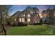 Elegant home featuring a stone and brick facade, manicured landscaping, and warm, inviting lighting at dusk at 116 Whispering Cove Ct, Mooresville, NC 28117