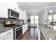 Granite counters, stainless appliances, and stylish backsplash enhance this modern kitchen with seamless connection to dining area at 1224 Horsesugar Rd, Clover, SC 29710