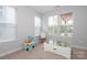 Well-lit bedroom with neutral walls and carpet, featuring multiple windows and play area at 136 Morgans Branch Rd, Belmont, NC 28012