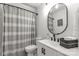 Well-lit bathroom showcases an oval mirror, gray shower curtain, vanity with storage and a toilet at 1527 Meadow Glen Ln, Rock Hill, SC 29730