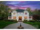 Elegant white home with a fountain in circular driveway and manicured landscaping against a beautiful evening sky at 200 Highland Forest Dr, Charlotte, NC 28270