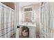 Bathroom with a large white sink, Hollywood mirror and colorful shower curtains at 237 Palaside Ne Dr, Concord, NC 28025